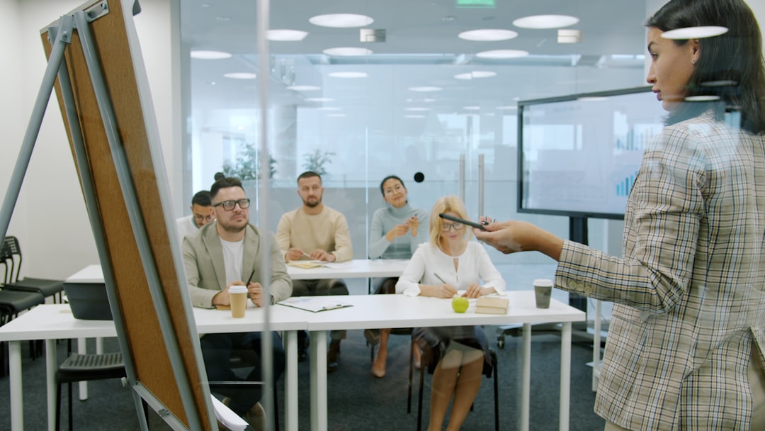 Managers men and women are listening to employee young lady making report in conference room talking and gesturing using flipchart whiteboard.